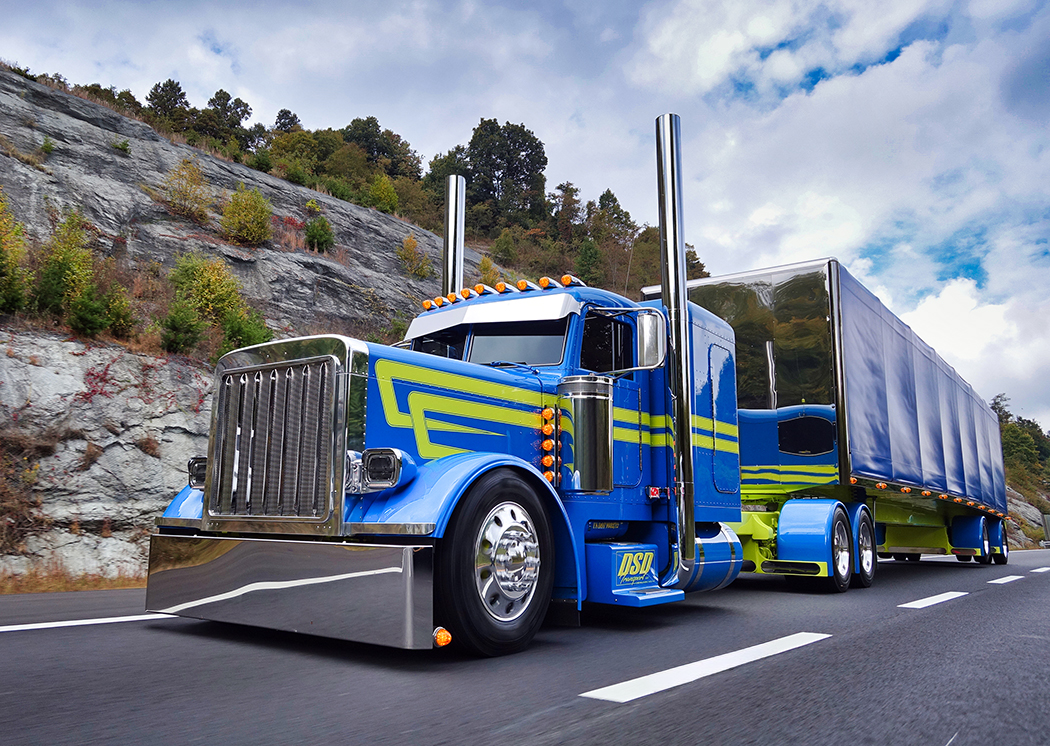 Teal Peterbilt 389 with yellow stripes on road